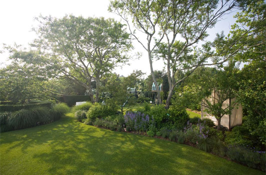 title:At the rear of the property, a children's garden was installed. This garden features a play set, a story telling area, a sunken trampoline, and a covered day bed.