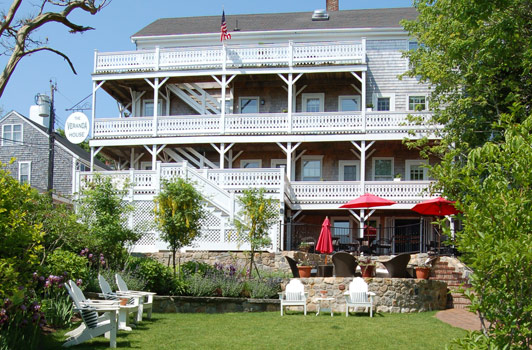 title:View of the Veranda House from the main entrance gate with the main path in the foreground. The lower seating wall made from collected stones on site. The middle terrace sits at the center, with the breakfast patio up above.